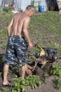 Man dipps potatoes with agromashine motorcultivator. Bashkortostan, Russia - 12 June, 2021.