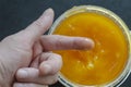 Man dips his index finger into an organic yellow bee honey in  cylindrical plastic container Royalty Free Stock Photo