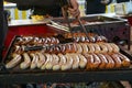 Man with dirty hands turns sausages with tongs on a street grill, typical food on a German county fair or Christmas market,