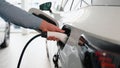 A man disconnects a charging cable to an electric car in showroom