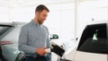 A man disconnects power connector into luxury EV car in dealership