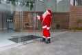 Man disguised as Santa Claus at Christmas enters through a glass door in a modern building Royalty Free Stock Photo
