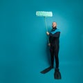 Man in diver wear holding plastic mop against  blue studio wall banner background Royalty Free Stock Photo