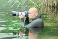 A man in a diving suit in the water with slr camera