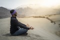 Man do Yoga pose on the rock within orning. Middle-aged sportsman practicing yoga and meditation in mountains with luxury view