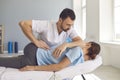 Man doctor chiropractor or osteopath fixing lying womans back in manual therapy clinic Royalty Free Stock Photo