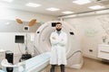 Man doctor in CT scan computed tomography room in medical clinic. Handsome bearded doctor in medical robe with computed Royalty Free Stock Photo