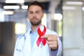 Man doctor holding a red ribbon in his hand for december world aids day, an international day of protecting people from
