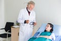 Man doctor using thermometer and examining asian woman fever patient with follow up treatment at hospital