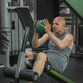 Man does exercises with a ball to pump the muscles of the press on a sports bench Royalty Free Stock Photo