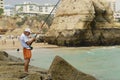 Man does fishing at Praia da Rocha beach in Portimao, Portugal.