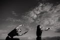 The man does stretching, the woman does exercises with a dumbbell. Black and white photo. Sky backgroung Royalty Free Stock Photo