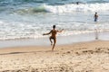 A man does Yoga exercises on the sand of beach while other people walk by Royalty Free Stock Photo