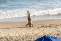 A man does Yoga exercises on the sand of beach while other people walk by Royalty Free Stock Photo