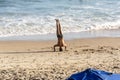 A man does Yoga exercises on the sand of beach while other people walk by Royalty Free Stock Photo