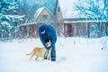 A man with a dog walks in a village in a snowy winter Royalty Free Stock Photo