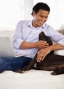 Man, dog and face with laptop on couch for bonding, playing or happiness with remote work in home. Animal, person and Royalty Free Stock Photo