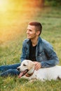 Man and dog labrador sits on grass Royalty Free Stock Photo