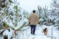 Man with a dog walks in snowy forest Royalty Free Stock Photo