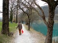 Man with the dog near the mountain lake with turquoise blue water and old tree