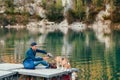 Man dog owner and friend beagle dog on the wooden pier on the mountain lake and enjoying the landscape during their walking in the