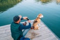 Man dog owner and friend beagle dog on the wooden pier on the mountain lake during their walking in the autumn season time. Male