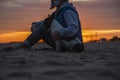 Man with dog sitting on beach against sky during sunset Royalty Free Stock Photo
