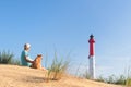 Man and dog sitting near lighthouse at the beach Royalty Free Stock Photo