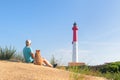 Man and dog sitting near lighthouse at the beach Royalty Free Stock Photo