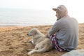 Man and dog sitting together on sand beach on vacation time. Royalty Free Stock Photo