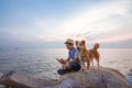 A man and a dog sitting together on the stone near the sea Royalty Free Stock Photo