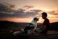 A man with a dog at sunset. walk with a pet. Australian Shepherd and owner in nature