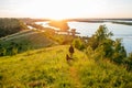 Man with dog traveling on sunset, nature beautiful landscape, view from the top of the green hill on the river. Royalty Free Stock Photo
