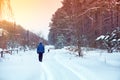 A man with a dog walks along a snowy country road between a pine forest and a village. The man walks in the countryside in winter Royalty Free Stock Photo