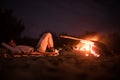 Man doing camping and lying on the beach near fire at night