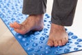 Man doing flatfoot correction gymnastic exercise walking on massage mat at home Royalty Free Stock Photo