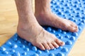 Man doing flatfoot correction gymnastic exercise walking on massage mat at home Royalty Free Stock Photo
