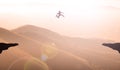 Man Doing A Great Jump Over Cliff Mountains Sunset.