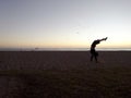 Man Doing Handstand on Beach at Sunset with Boats on Ocean Royalty Free Stock Photo