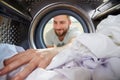 Man Doing Laundry Reaching Inside Washing Machine Royalty Free Stock Photo