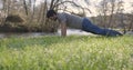 Man doing pushups by the river in grass on a bright day.