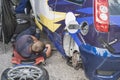 Man is doing sports car maintenance, the car is broken and without wheels. Mechanic lying near automobile and repair vehicle