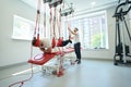 Man doing suspension exercise at rehabilitation center with physiotherapist