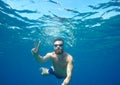 Man doing underwater selfie shot with selfie stick in blue sea