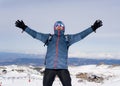 Man doing victory sign after peak summit trekking achievement in snow mountain on winter landscape