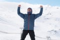 Man doing victory sign after peak summit trekking achievement in snow mountain on winter landscape