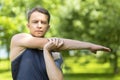 Man doing workout in park outdoor. muscular guy stretching his arm. sport, fitness and healthy lifestyle concept. Cross-Body Royalty Free Stock Photo