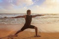 Man doing yoga asana Virabhadrasana 1 Warrior Pose on beach