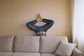 Man doing yoga behind beige couch