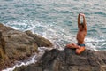 Man doing yoga exercise on the deserted wild stone sea beach. Royalty Free Stock Photo